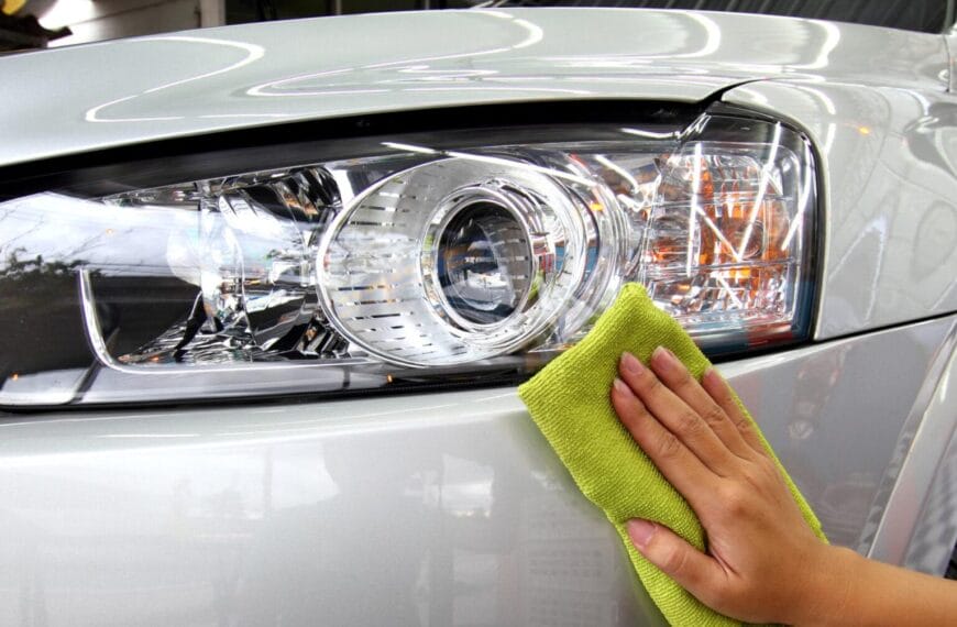 Cleaning a silver cars headlight with a green cloth at Iligan Carwash.
