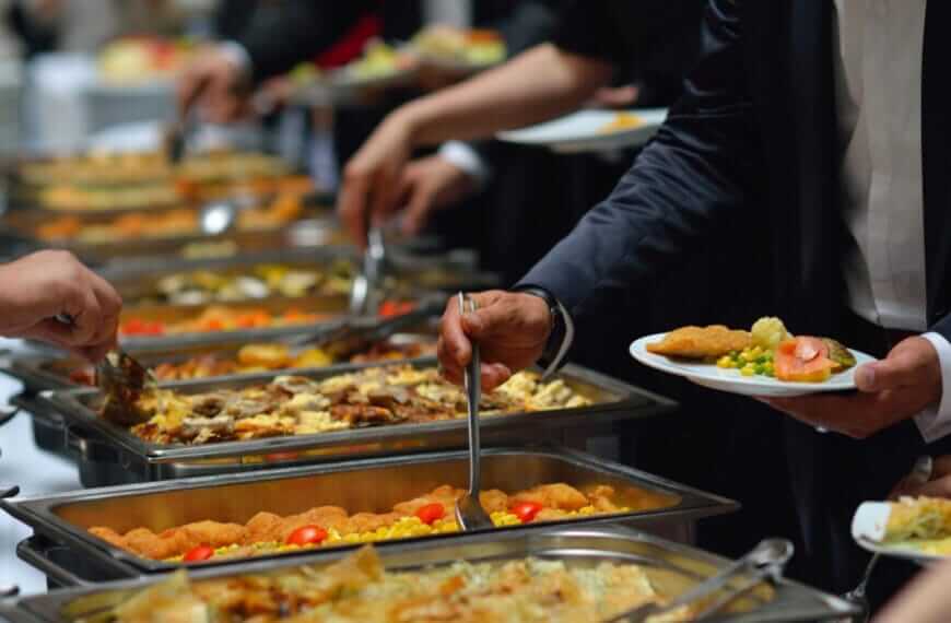 People enjoying a buffet with various dishes, showcasing catering in Iligan, plates filled with diverse foods.