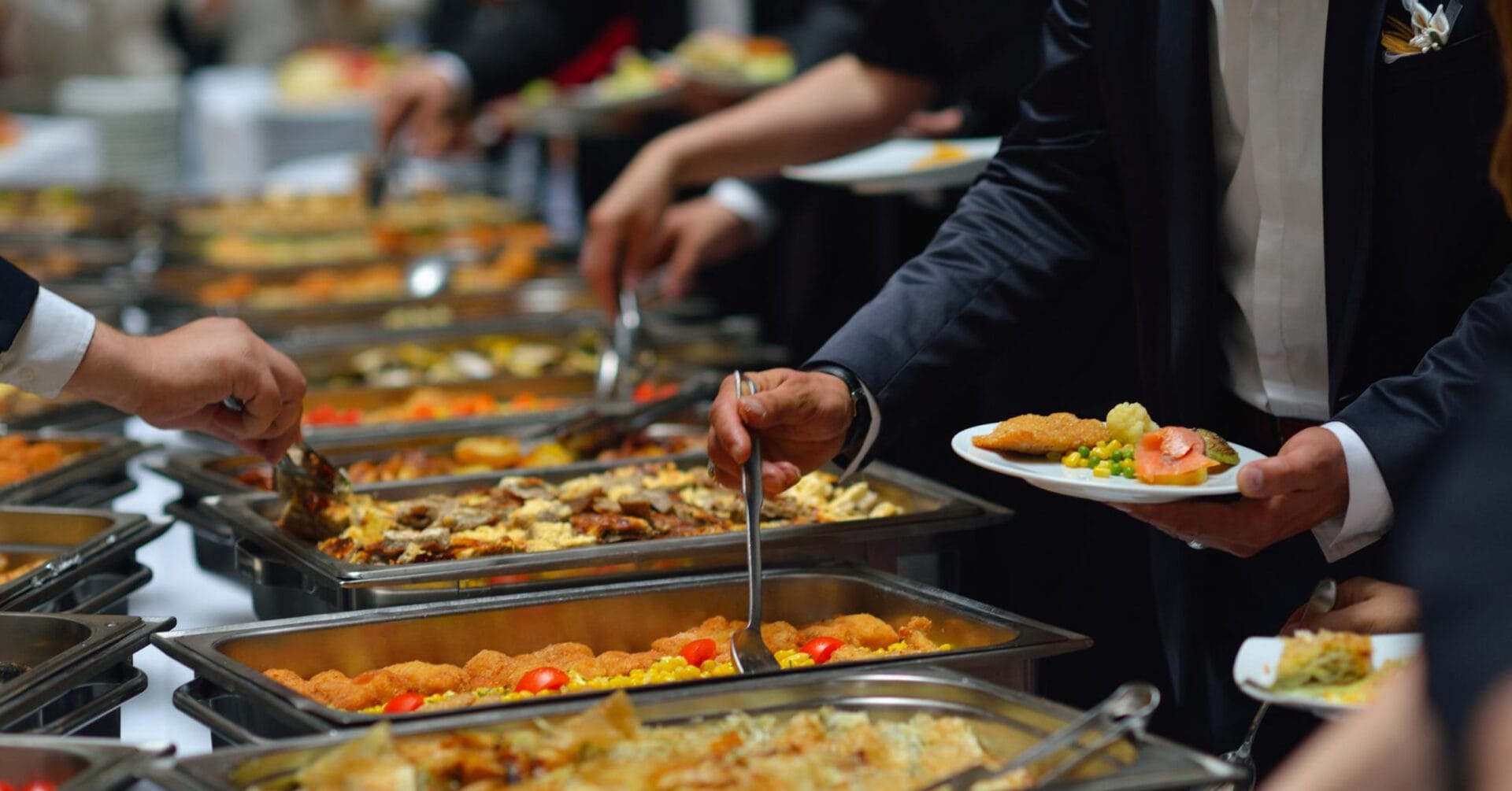 People enjoying a buffet with various dishes, showcasing catering in Iligan, plates filled with diverse foods.