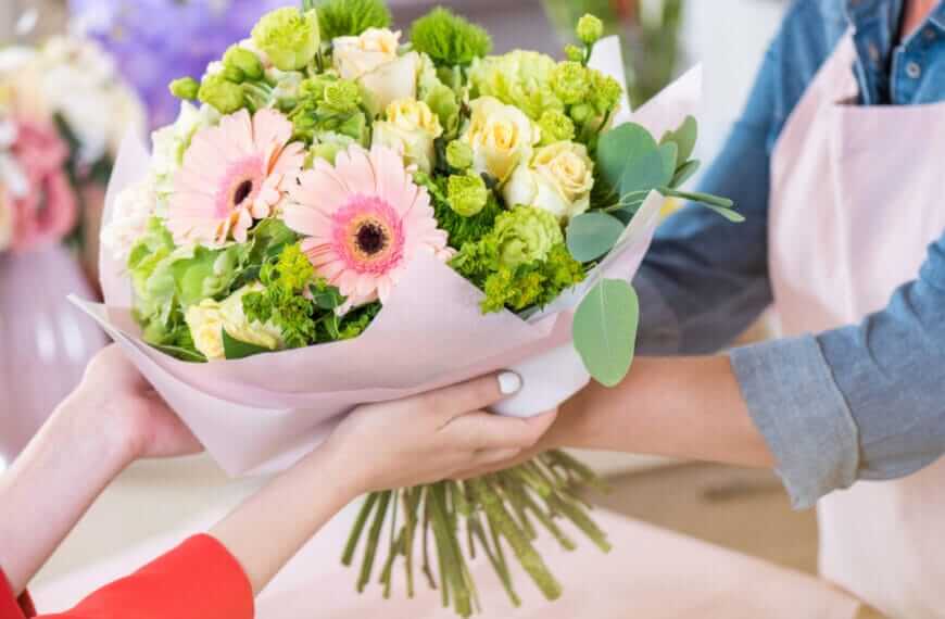 Hands exchange a bouquet of pink gerberas and yellow roses, wrapped in pink paper, crafted by an Iligan flower shop.
