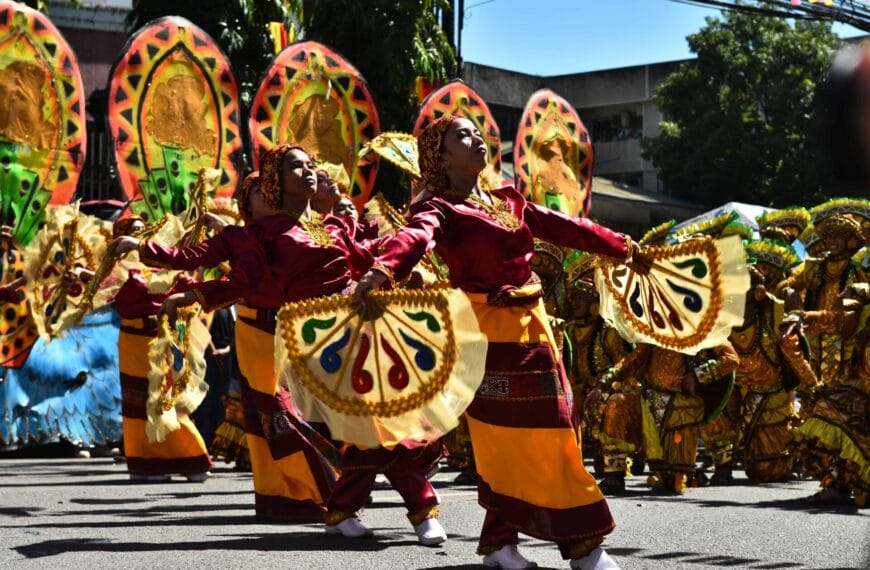dancers in colorful costumes with yellow fans light up a street festival parade for the front page template.