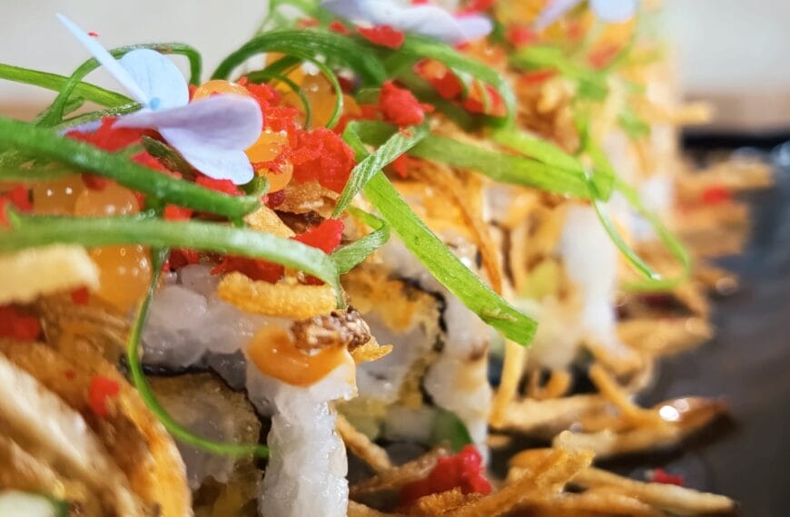 close up of urban cafés signature sushi rolls topped with fish roe, green onions, and edible flowers.