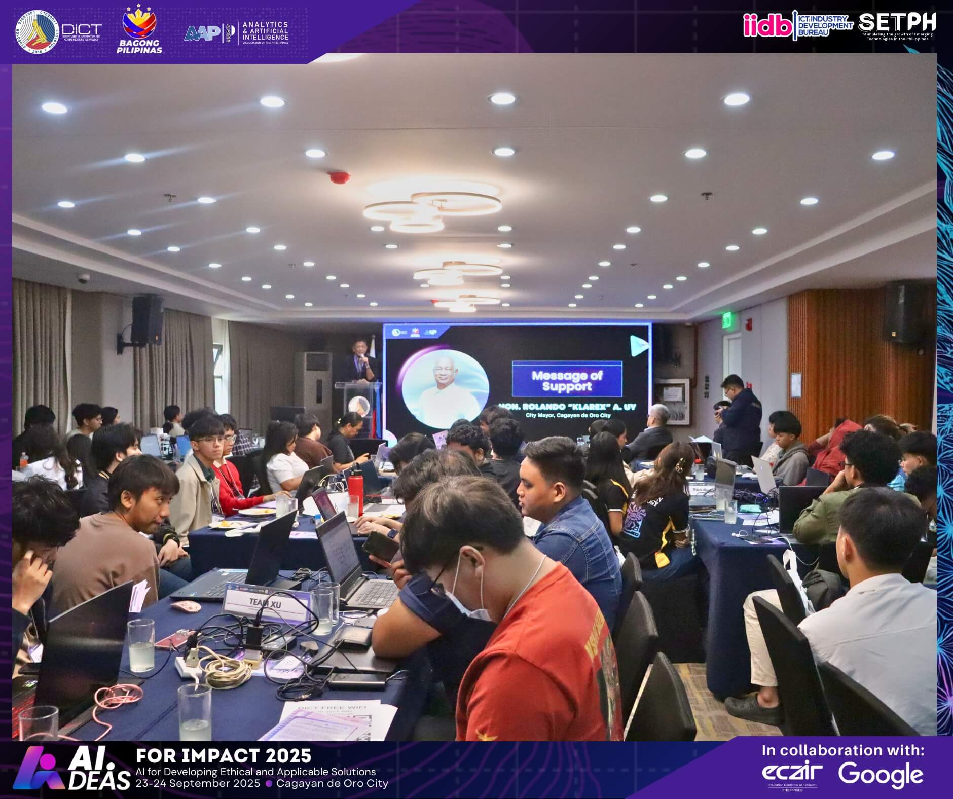 a conference room in mindanao filled with people at laptops, watching an ai innovation 2025 presentation up front.