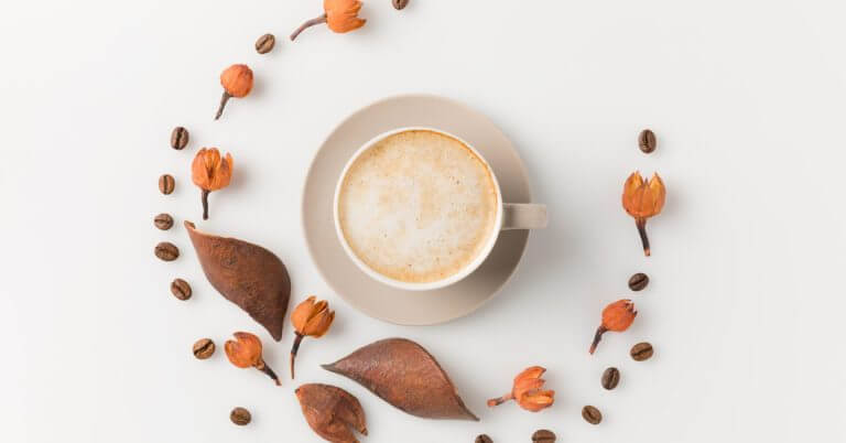 a cup of philippine coffee on a saucer sits among dried leaves, orange buds, and beans—perfect for makati mornings.
