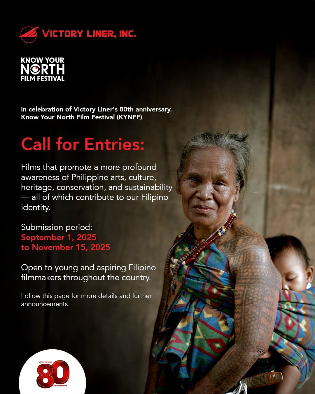 an elderly woman in traditional attire and beaded jewelry stands, arms crossed, against a blurred natural background.
