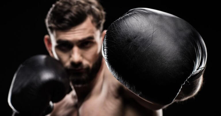a male boxer with a beard throws a punch, ready for the engkwentro v2 boxing tournament, against a dark background.