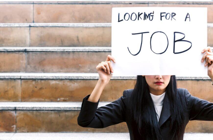 woman in business attire sits on steps holding a sign, "looking for a job," seeking iligan city jobs.