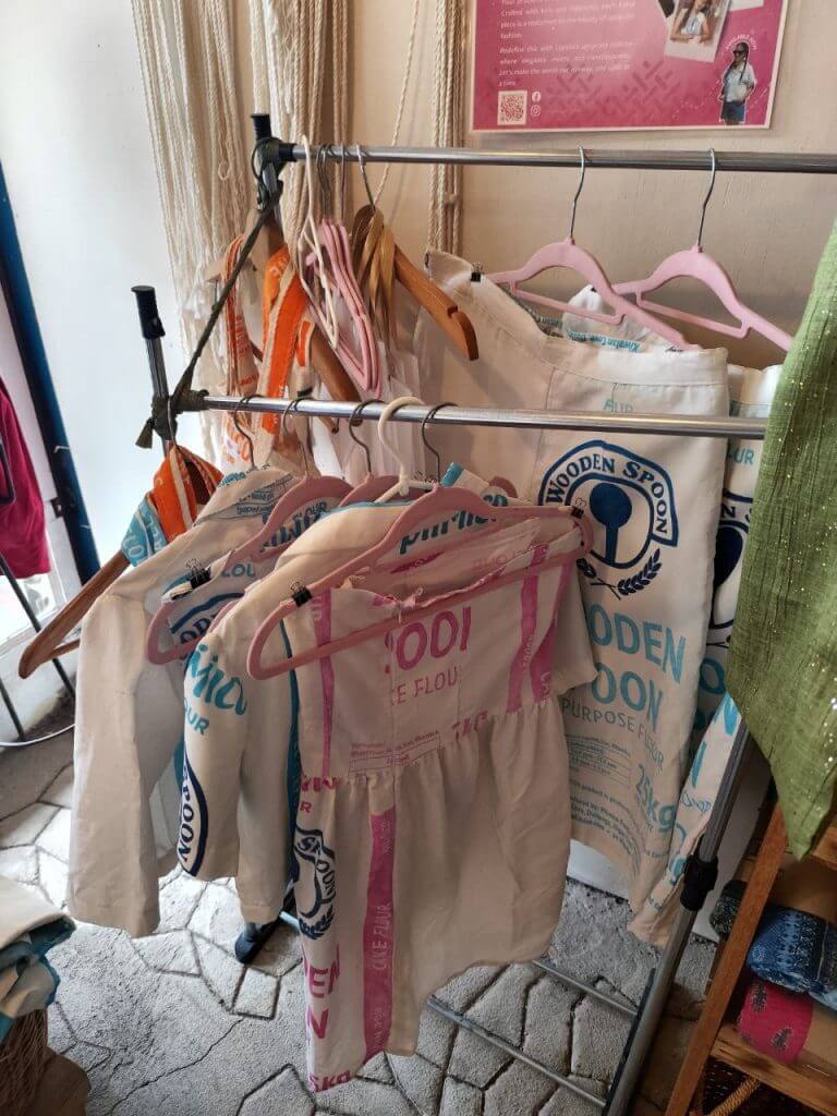 shirts and aprons made from printed flour sacks, perfect iligan arts crafts, hang on wooden and pink hangers.