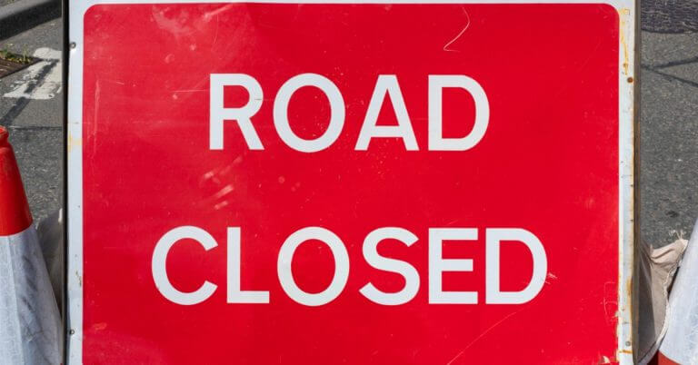 a red road closed sign marks street closures in iligan during the vibrant diyandi festival.