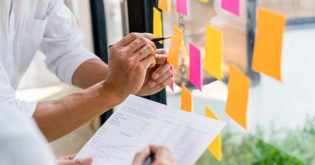 two skilled professionals discuss colorful sticky notes and data, showcasing virtualtask ph's online services.