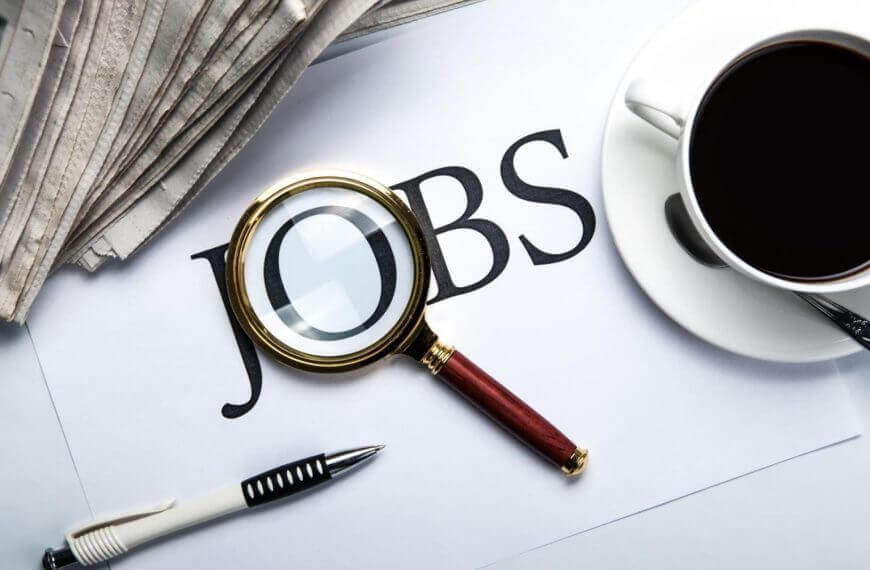 a magnifying glass over the word jobs, with a pen, coffee cup, newspapers—ideal for iligan jobseekers.