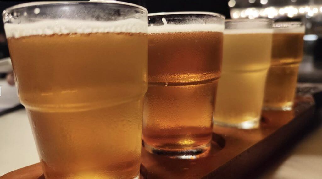 four glasses of beer on a wooden tray, perfect for enjoying after an iligan adventure or tasting iligan food.