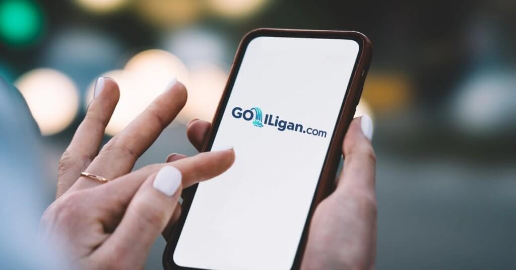 A hand holds a phone displaying the GoLilligan.com logo&mdash;discover where to buy SIM cards in Iligan City.