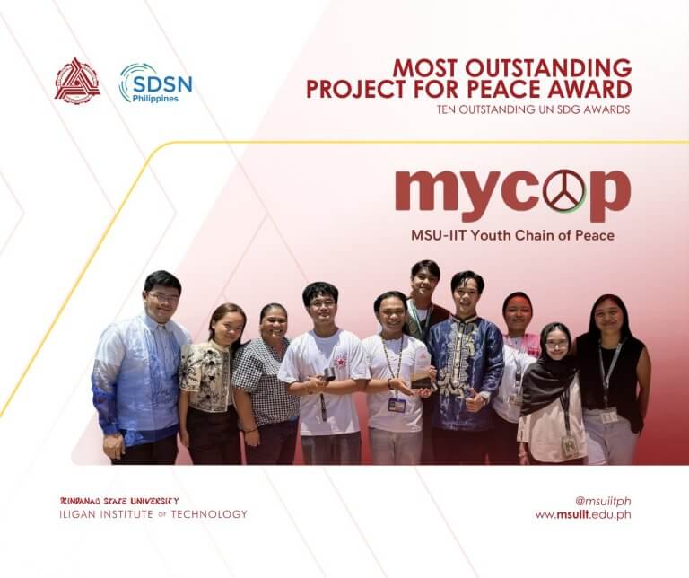 nine people stand smiling in a row, holding a certificate, beneath a most outstanding project for peace award banner.