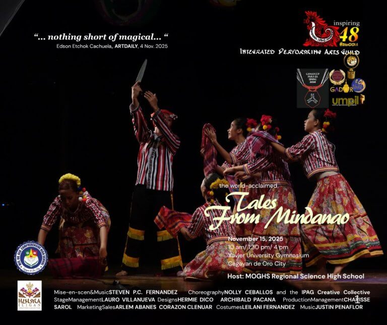 five dancers in colorful costumes perform with bamboo poles on a dark stage, mid movement, hands raised.