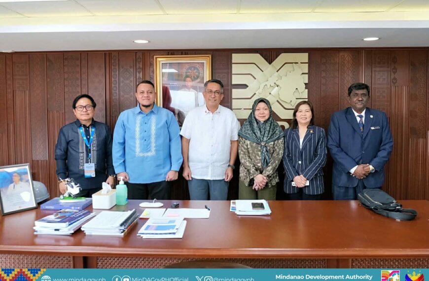 six people stand smiling behind an office desk, celebrating philippines chairmanship of bimp eaga in mindanao.