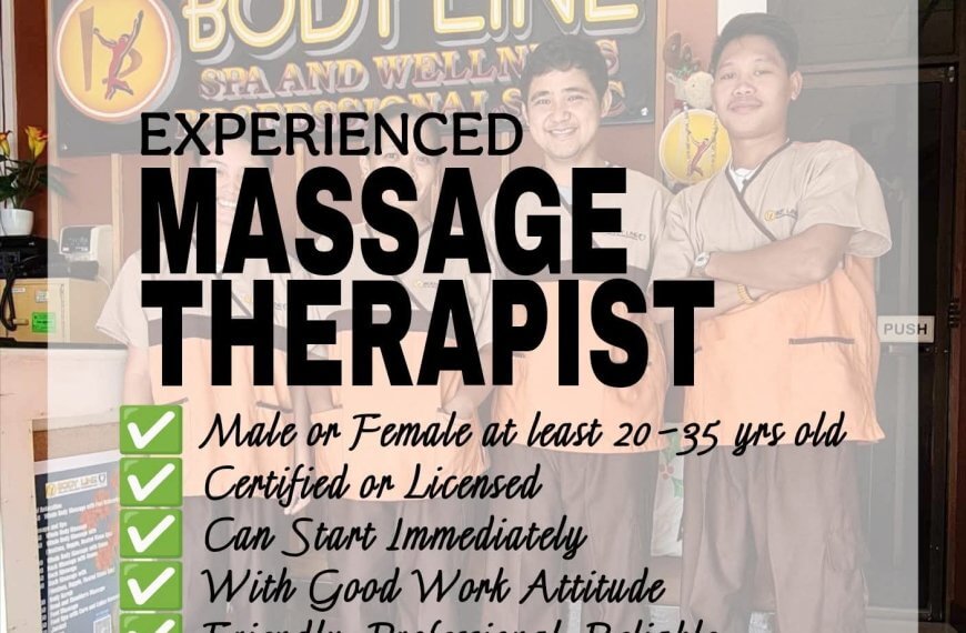 two smiling massage therapists stand in front of a body line spa sign, holding a “urgent hiring” notice.