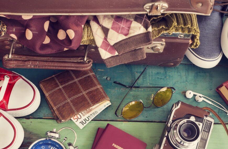 open suitcase with travel essentials on wood, highlighting region 10 tourism and community centered development.