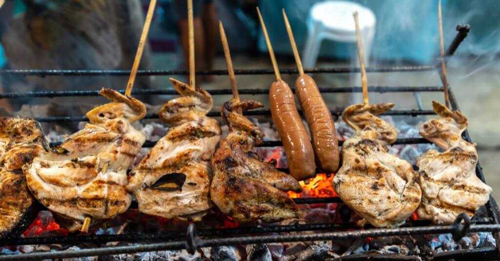 grilled chicken and sausages cooking over hot coals&mdash;a must visit spot for foodies in the mindanao travel guide.
