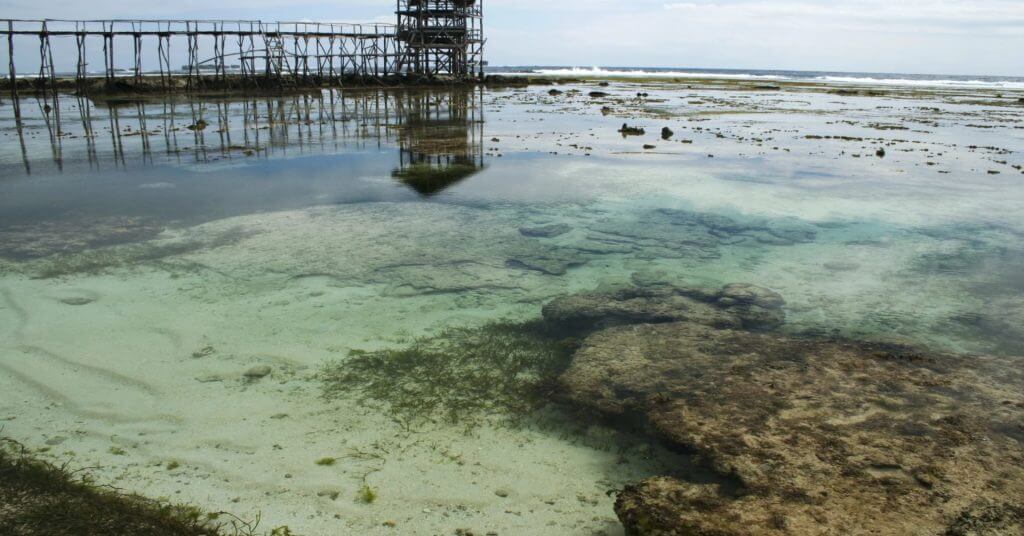 clear shallow tide pool with rocks and seaweed&mdash;one of mindanao travel guide&rsquo;s must visit spots; pier in background.
