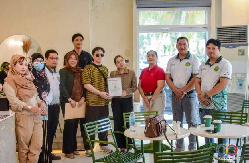 Halal Certified - meku coffee, some smiling with documents; tables and chairs are in front of them.