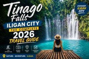 a woman in a hat sits on a dock facing tinago falls cascading into a blue pool, surrounded by lush greenery.